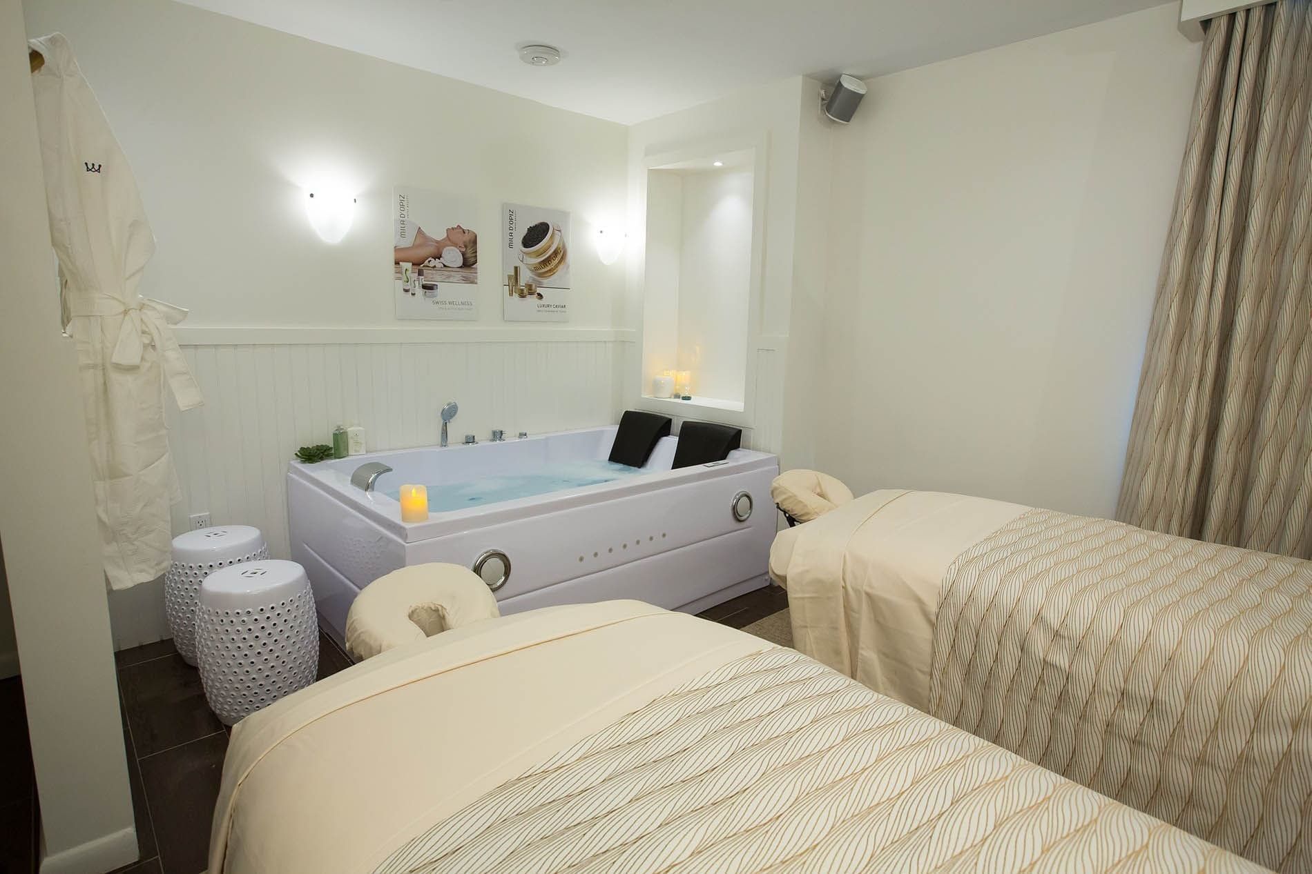Spa beds by a bathtub under warm wall lights surrounding a white robe at Warwick Paradise Island Bahamas