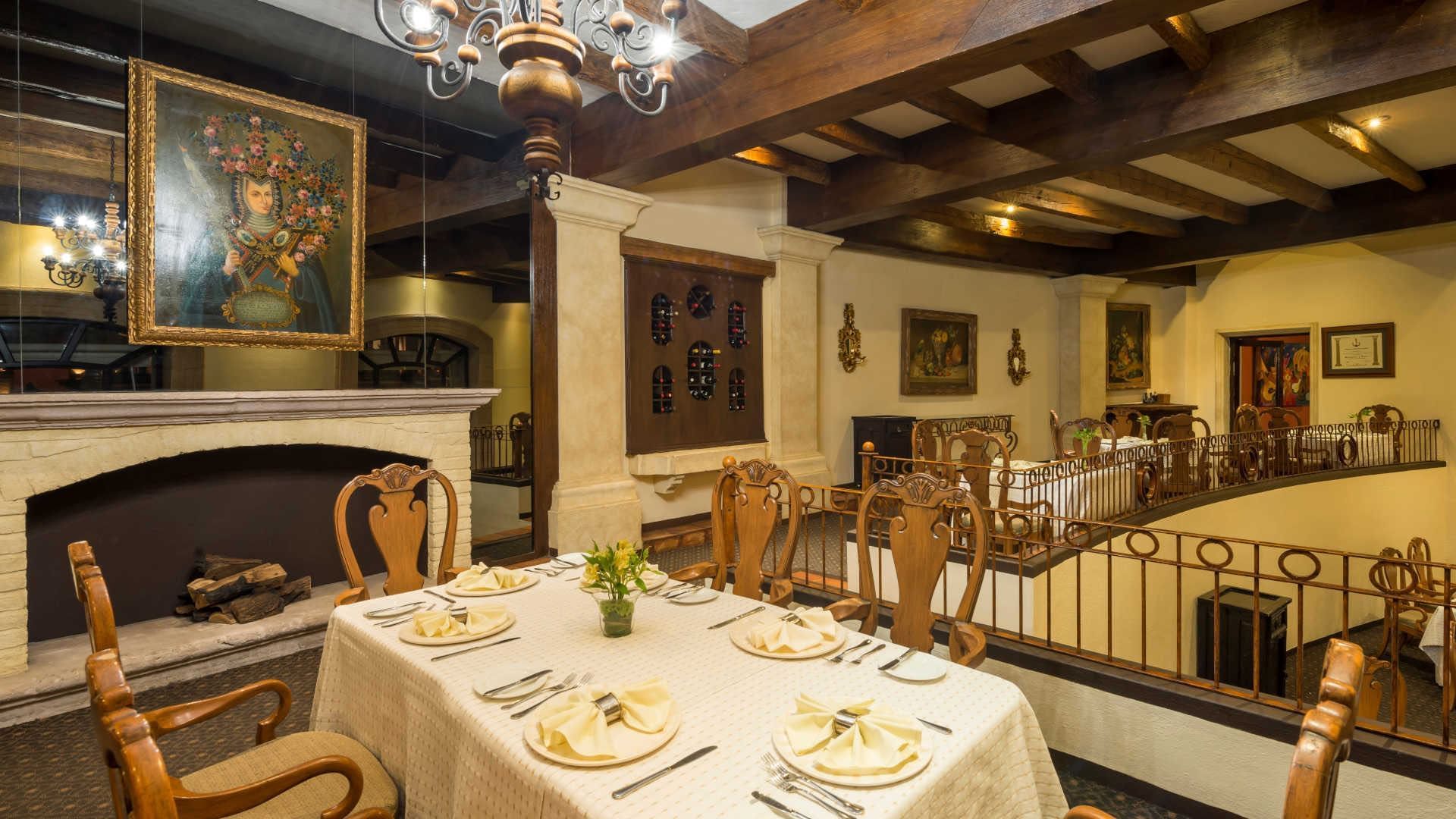 Upscale restaurant interior with a fireplace, ornate art, and wooden beams at Quinta Real Zacatecas