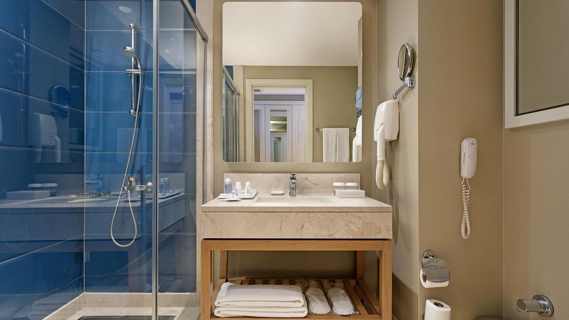 A stylish bathroom with blue walls and a glass shower at Titanic Deluxe Lara.