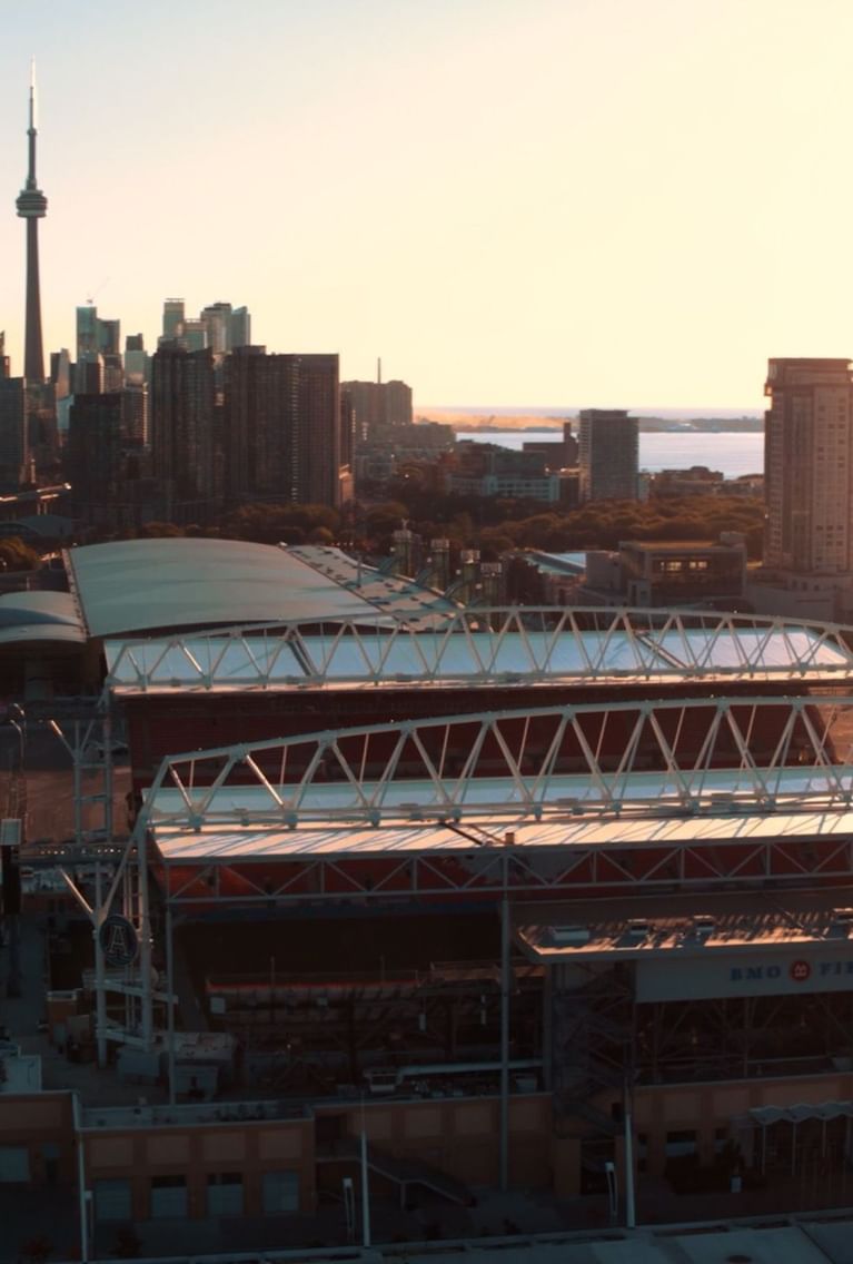 Aerial sunset view of BMO Field stadium by the Toronto skyline and CN Tower under a golden sky near Hotel X Toronto