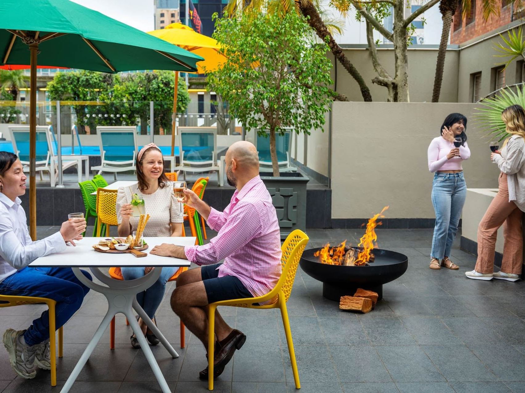 People dining & lounging on a deck by pool at Grand Chancellor Adelaide