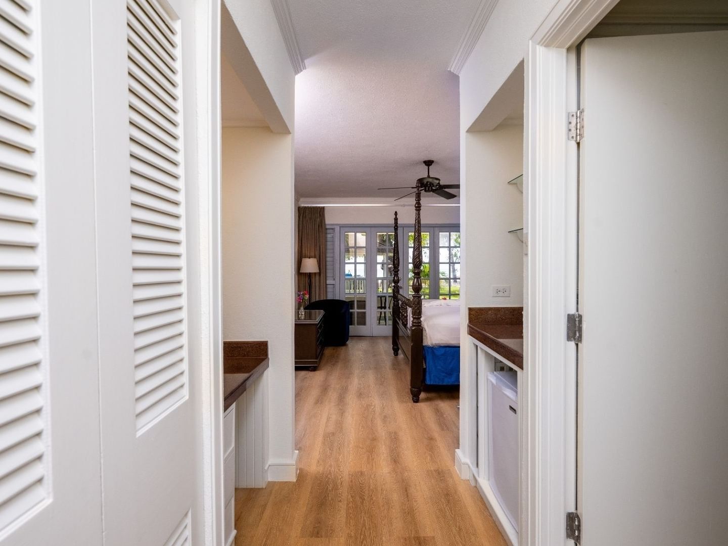 Elegant hallway leading to a bedroom with a canopy bed and a ceiling fan at Savannah Beach Hotel.