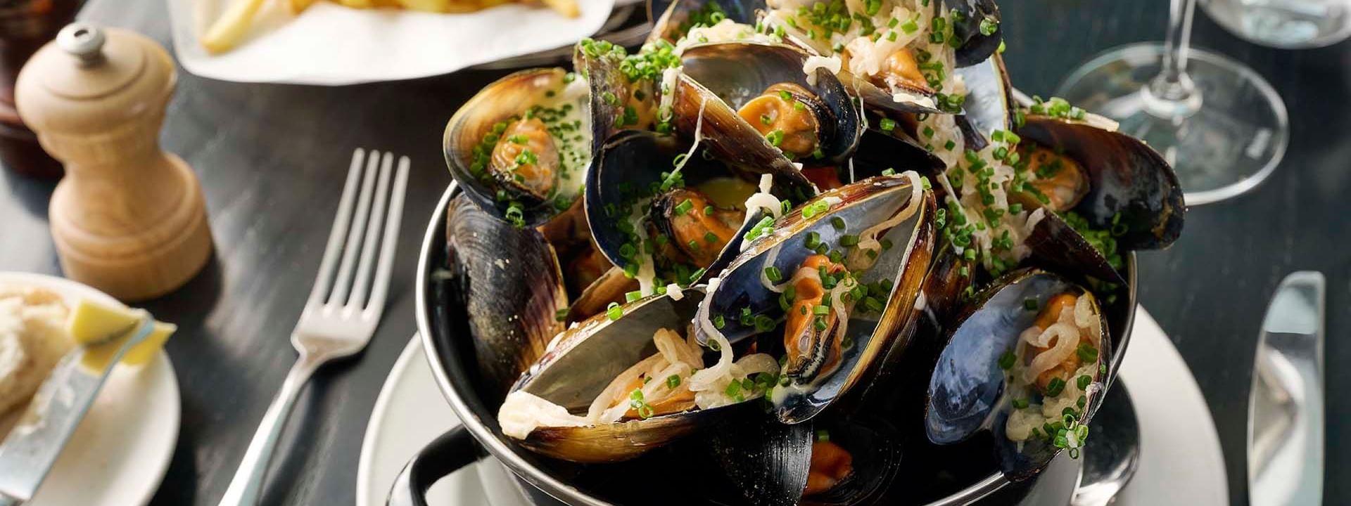 Pot of steamed mussels garnished with herbs served in Bistro Guillaume at Crown Hotel Melbourne