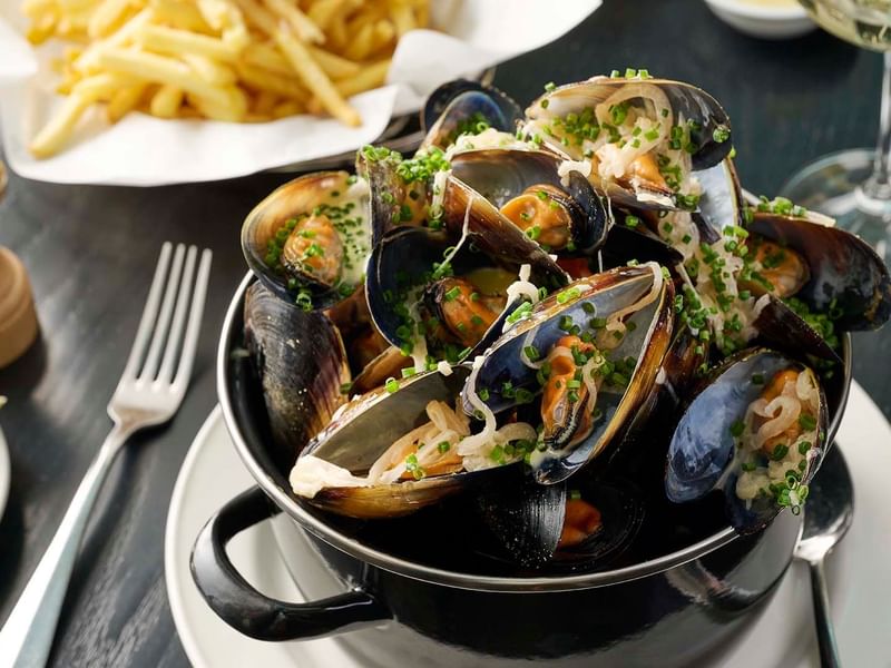 Pot of steamed mussels garnished with herbs served in Bistro Guillaume at Crown Hotel Melbourne