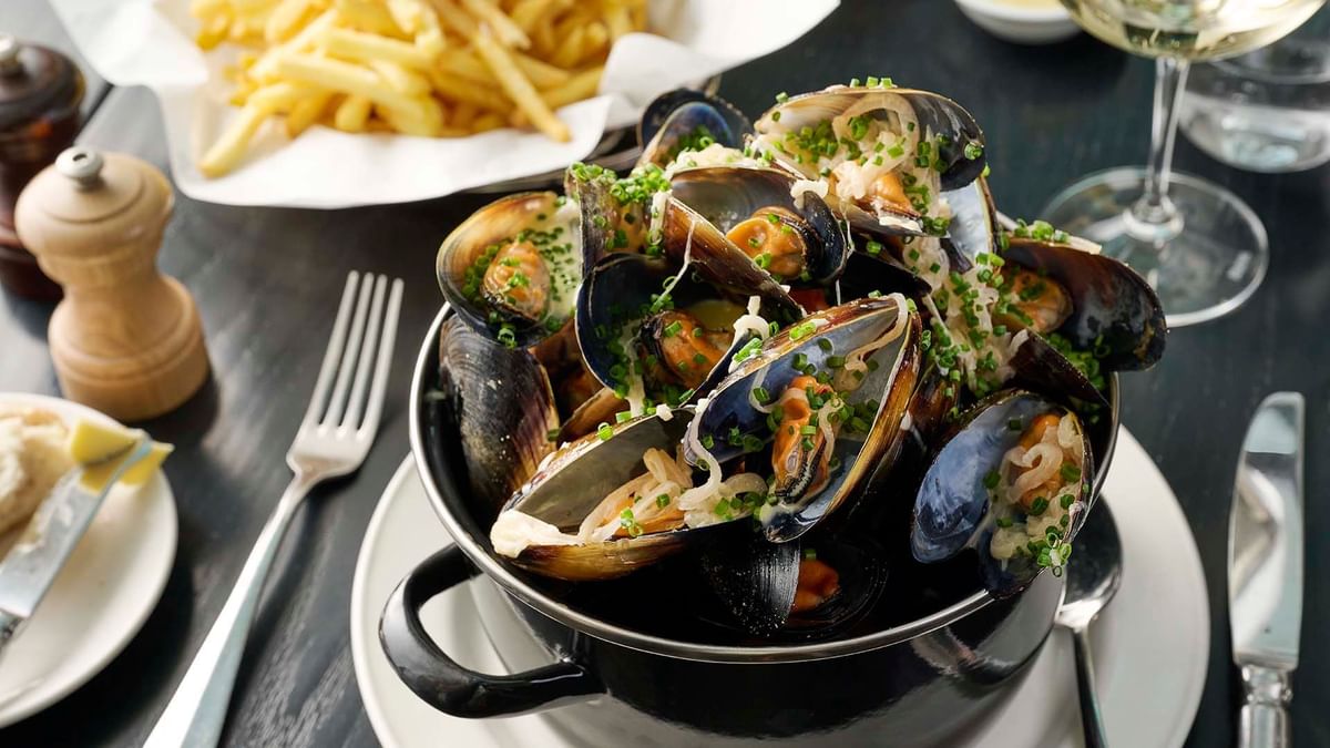 Pot of steamed mussels garnished with herbs served in Bistro Guillaume at Crown Hotel Melbourne