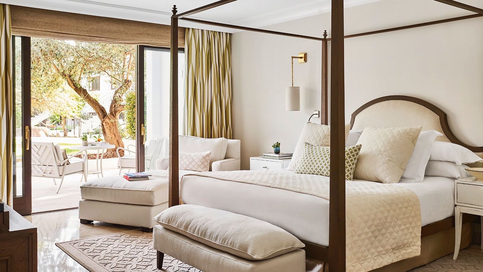 Junior Suite bedroom with a dark wood four-poster bed and glass doors opening to a private garden at Marbella Club
