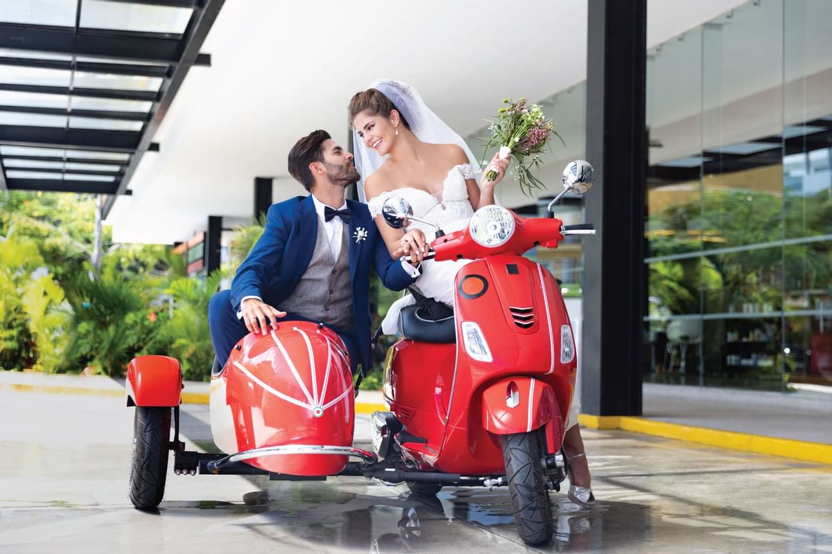 Una pareja de novios sentada en una moto con sidecar en el Fiesta Inn
