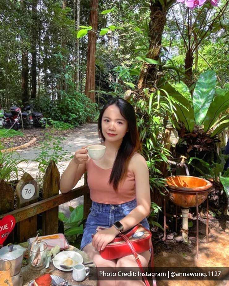 A lady elegantly held a coffee cup while capturing a picture at Kopi Hutan - Lexis Suites Penang