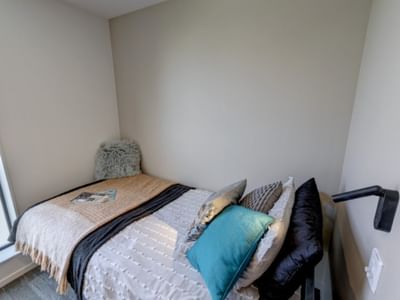 Minimalist bedroom with bed, colorful pillows, throws, and window view in Tupuārangi accommodation.