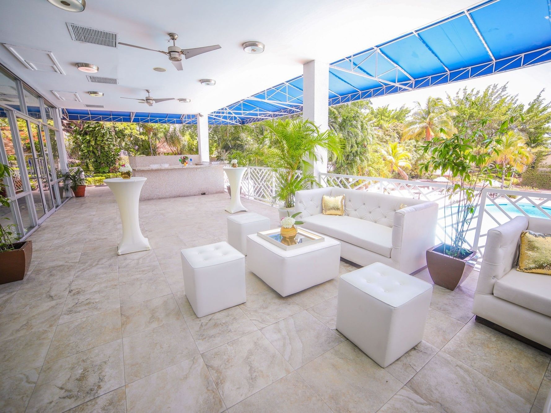 Legacy Terrace featuring white lounge seating and potted plants overlooking a pool area at Jamaica Pegasus Hotel