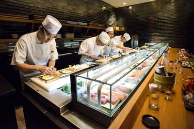 chefs rolling sushi at sushi bar