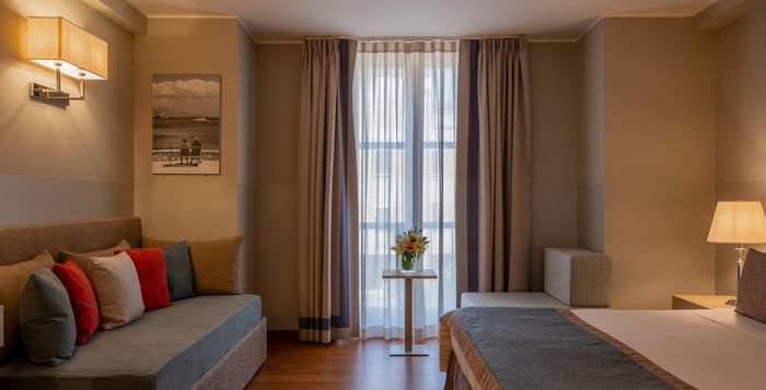 Modern hotel room with bed, floor-to-ceiling windows, and warm lighting at Grand Hotel Portovenere