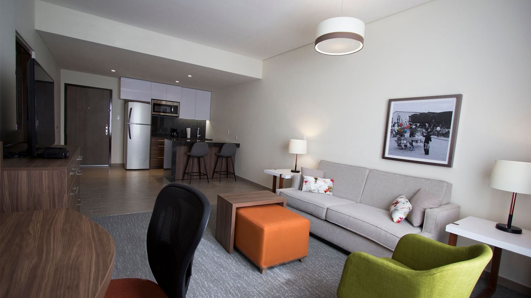 Modern living area featuring a sofa, a kitchenette, and a dining table at Fiesta Inn Suites Aeropuerto del Bajío