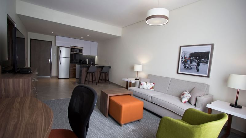 Modern living area featuring a sofa, a kitchenette, and a dining table at Fiesta Inn Suites Aeropuerto del Bajío