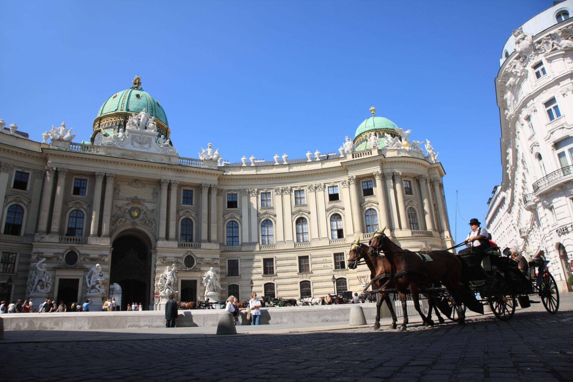 The Hofburg Palace in Vienna at Michaelerplatz with a traditional horse-drawn carriage in the foreground.