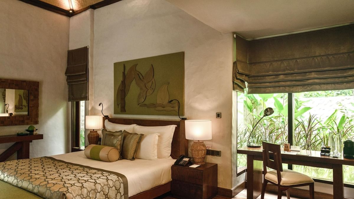 Cozy King-sized bed with a work desk and decorative art on wall in Garden Villa at The Banjaran Hotsprings Retreat