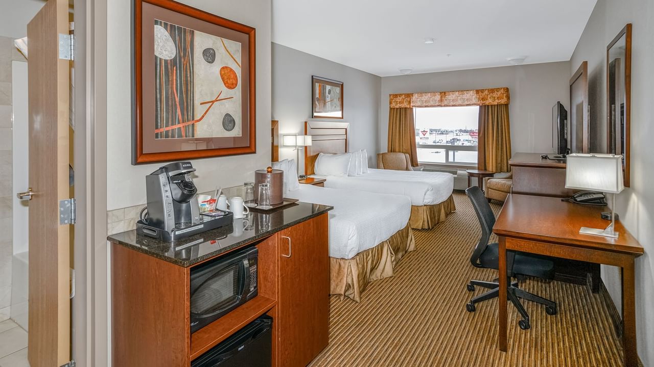 Hotel room with two queen beds, microwave, coffee machine, TV, work desk and chair