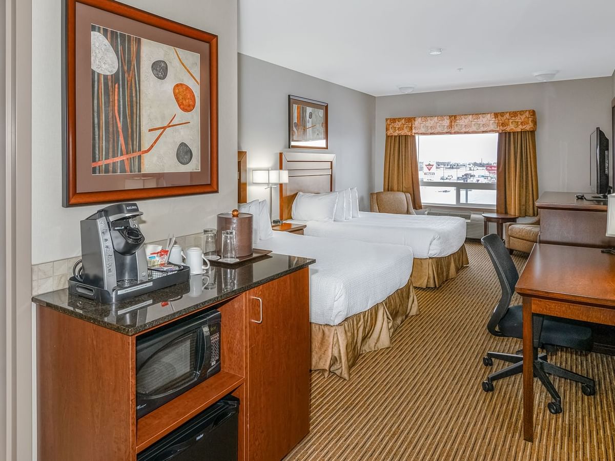 Hotel room with two queen beds, microwave, coffee machine, TV, work desk and chair