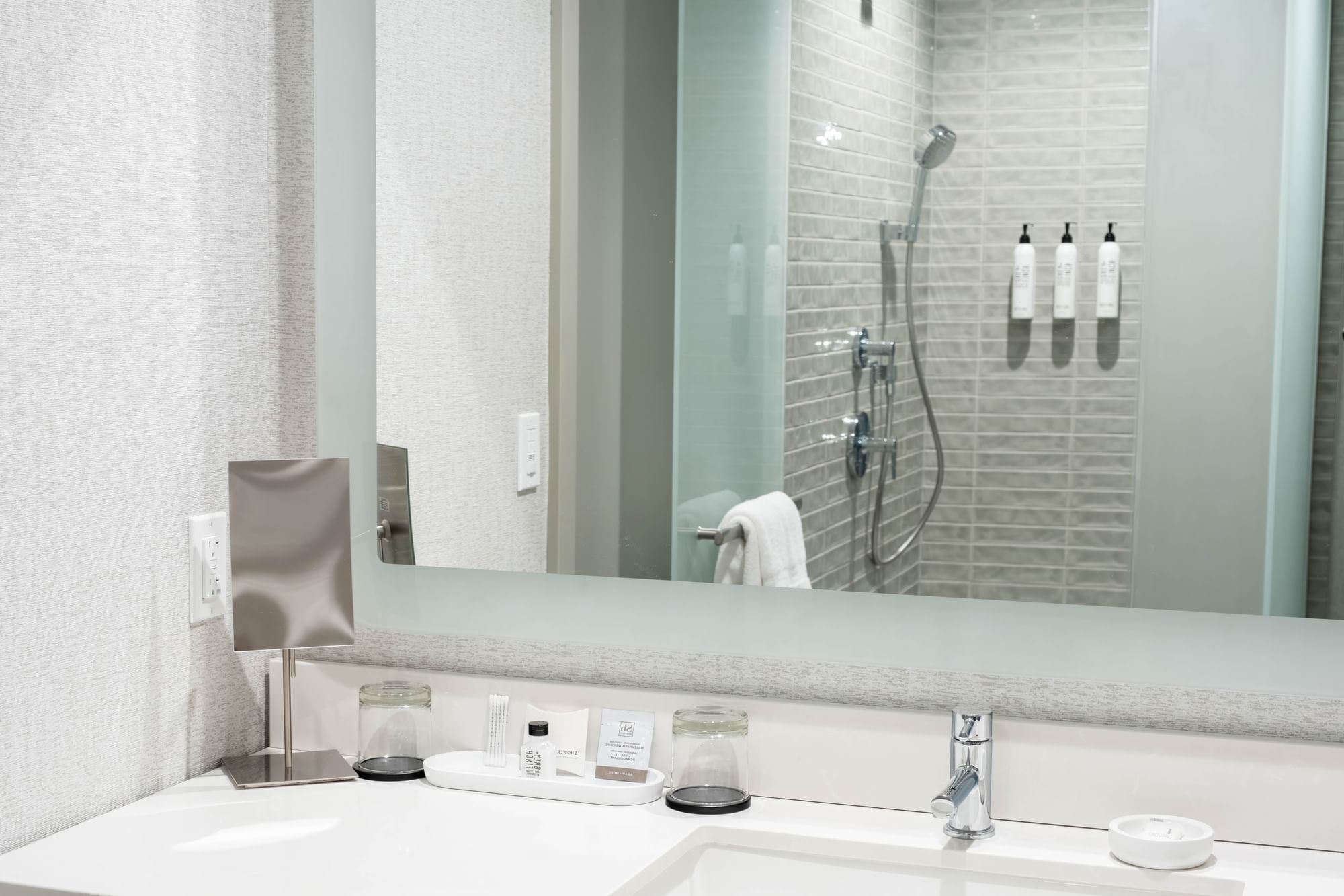 A clean and modern bathroom with a sink, mirror, and shower