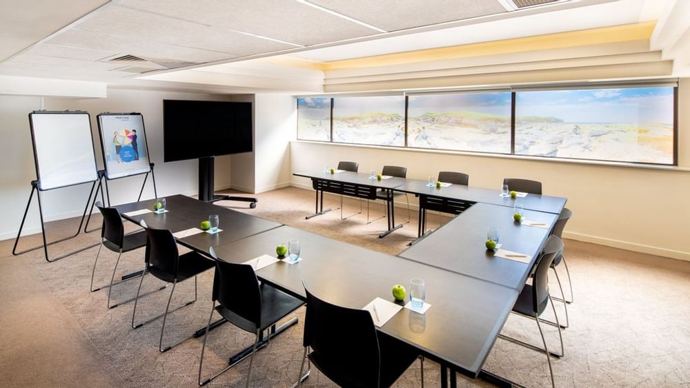 U-shape table set up facing TV by the windows in Waratah at Novotel Sydney International Airport