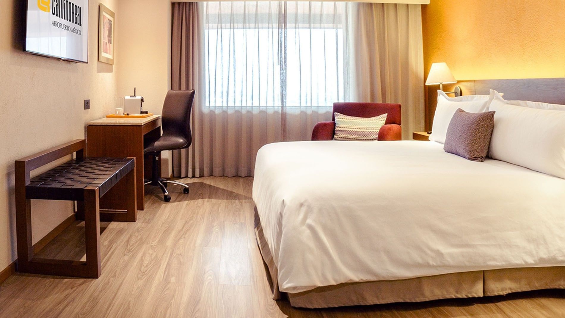 King bed with purple armchair and work desk by the window in King Camino Real Club at Camino Real Aeropuerto Mexico