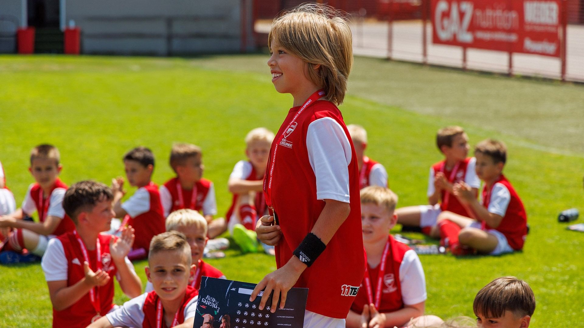 Junge Fußballer in roten Trikots auf dem Rasen, ein Junge steht hervor bei Falkensteiner Hotels & Residences