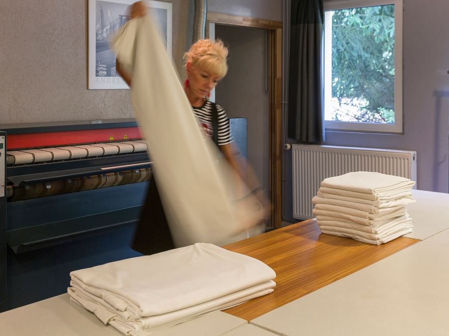 A maid is ironing the sheets at Hotel aster