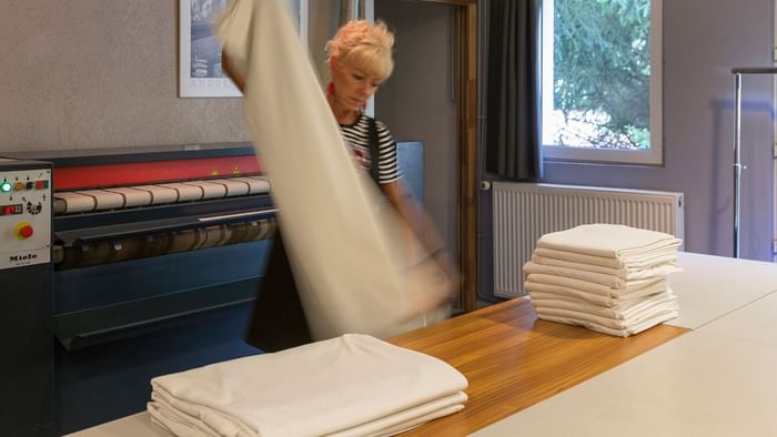 A maid is ironing the sheets at Hotel aster