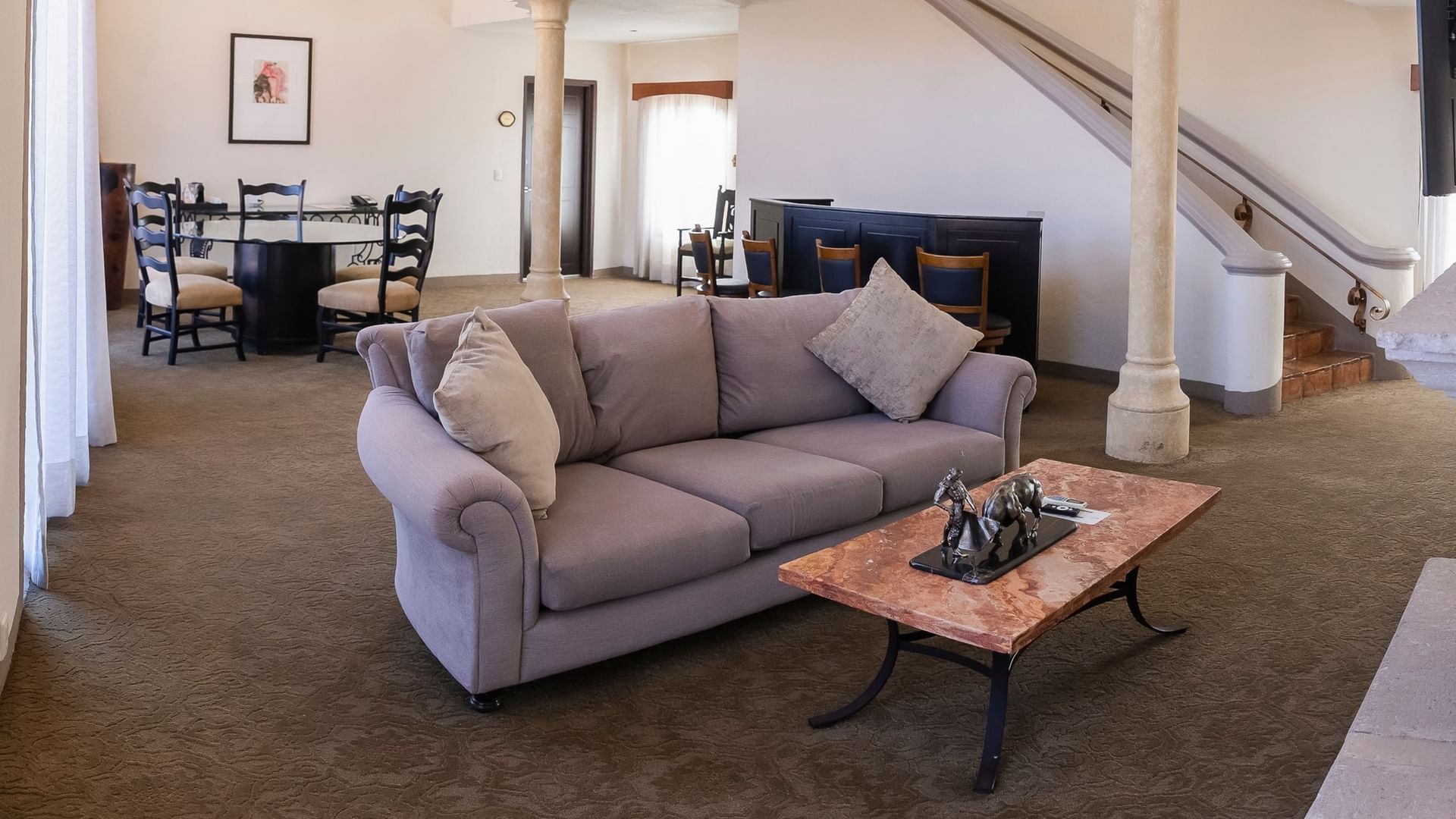 Spacious suite with gray sofa, dining area, and colonial architectural details at Quinta Real Zacatecas