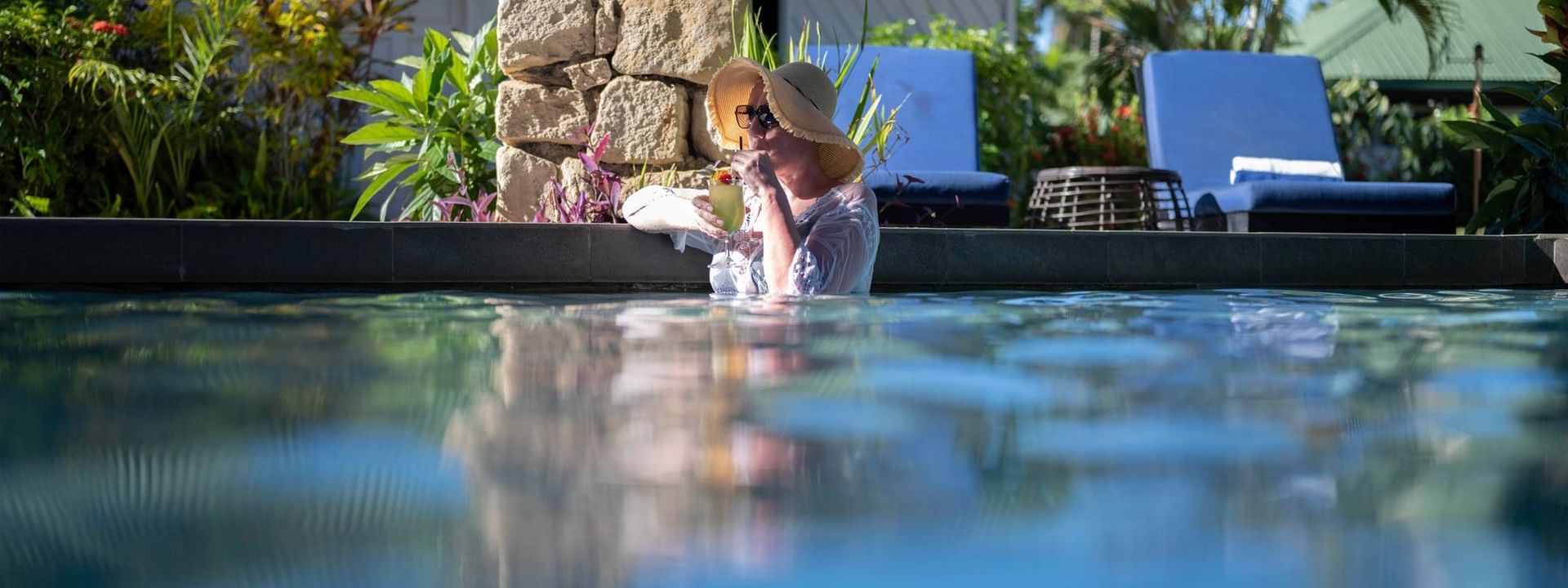 Guest a hat drinking a cocktail by a stone pillar in a swimming pool at TokaToka Resort Nadi Fiji