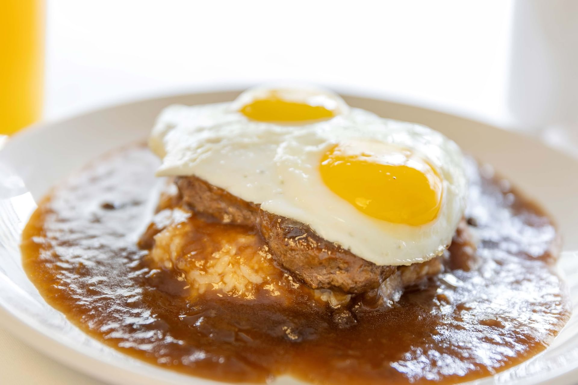 a close-up of a plate of food with two eggs on top of meat and gravy