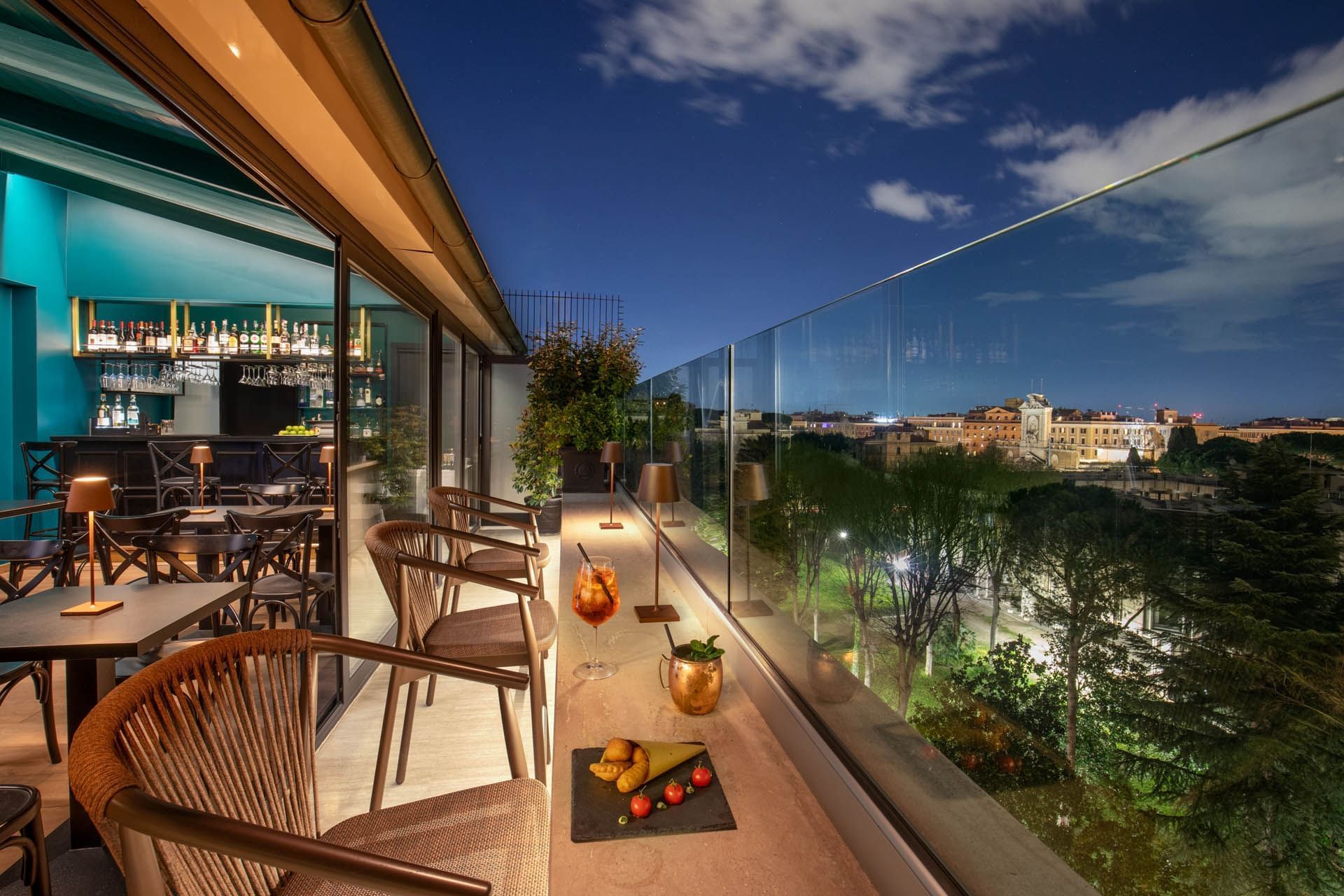 Charming Terrazza Costanza rooftop bar at The Guardian Hotel, with elegant seating and city views under the night sky