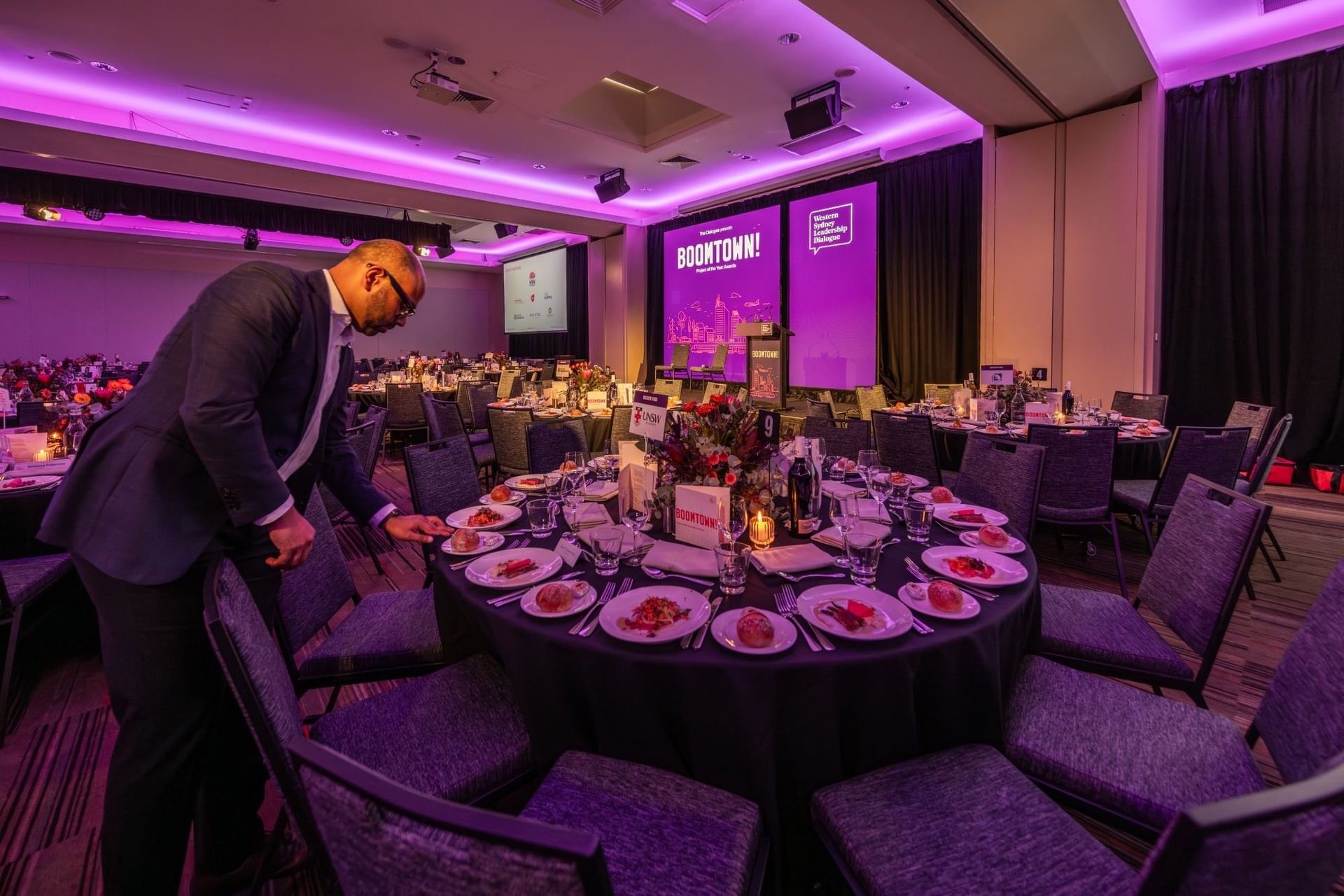 Staff member setting a banquet table in the Freshwater Room at Novotel Sydney Olympic Park