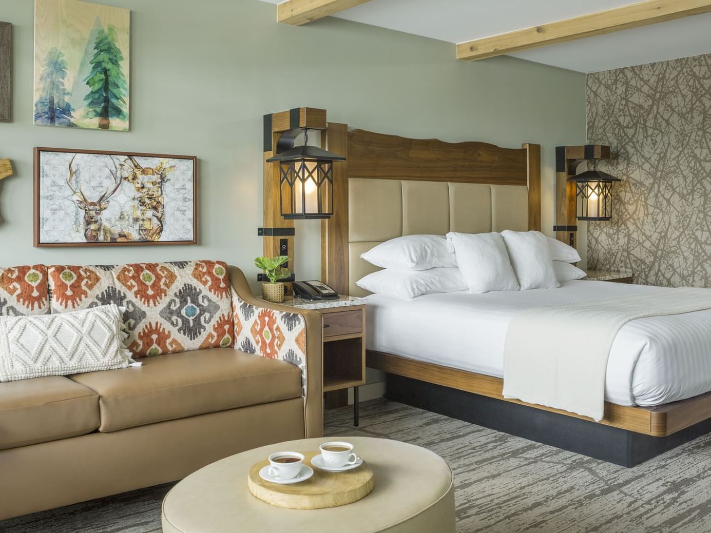 A room with a king bed, couch & a pouf table at Peaks Resort