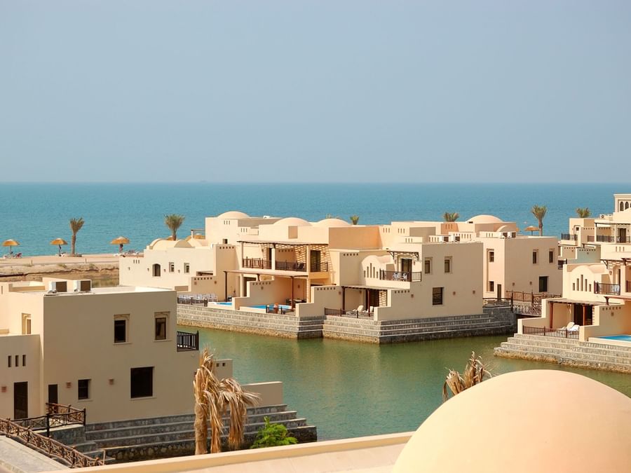 Luxury Ras Al Khaimah villas with terraces overlooking a canal, under a clear blue sky near DAMAC Hotels & Resorts