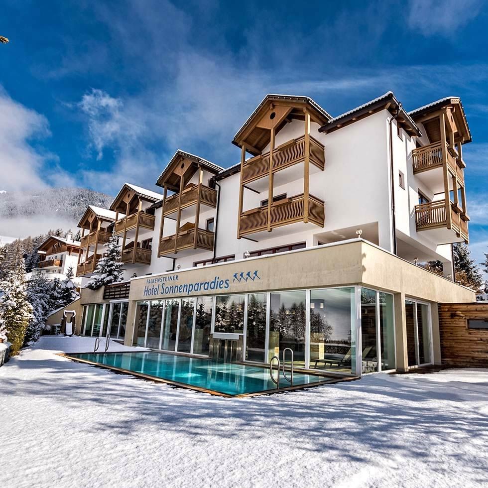 Schneebedecktes Hotel Sonnenparadies mit Pool im Winterzauber in Terenten.