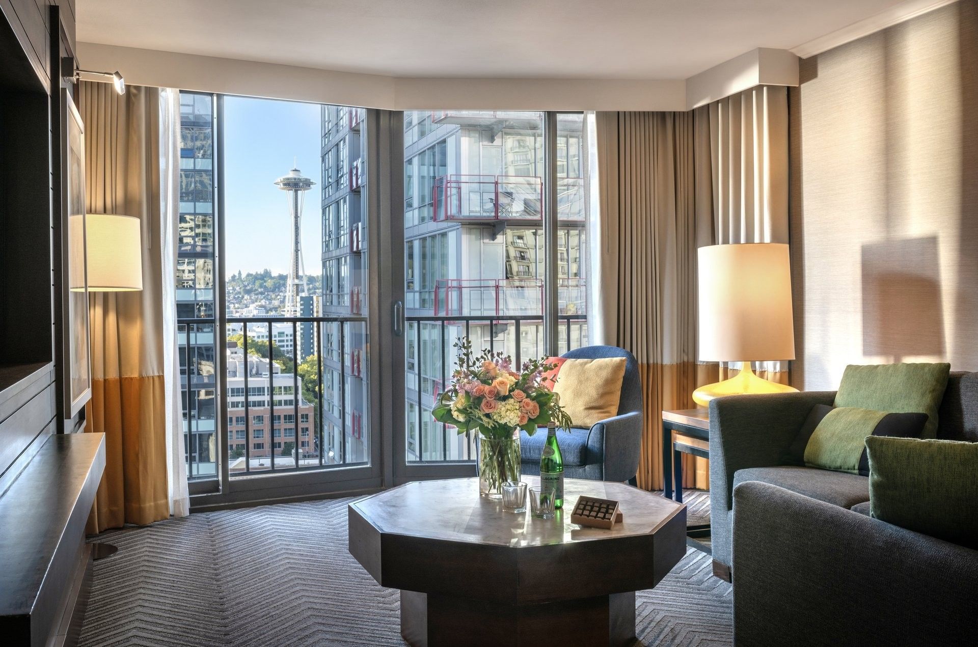Magnolia Suite with Octagonal table by a sofa and armchair under a view of the Space Needle at Warwick Seattle