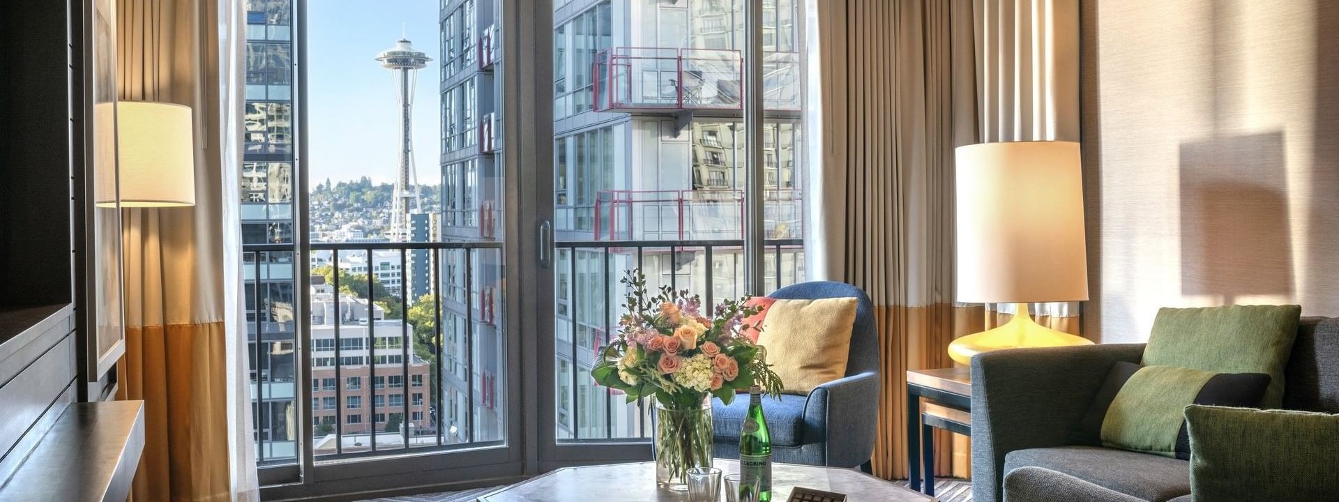 Magnolia Suite with Octagonal table by a sofa and armchair under a view of the Space Needle at Warwick Seattle