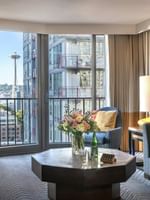 Magnolia Suite with Octagonal table by a sofa and armchair under a view of the Space Needle at Warwick Seattle