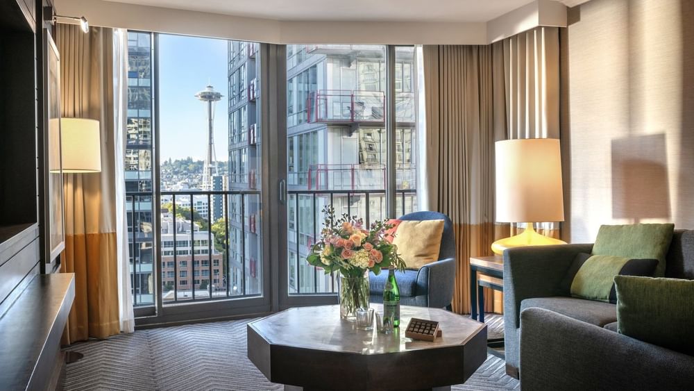 Magnolia Suite with Octagonal table by a sofa and armchair under a view of the Space Needle at Warwick Seattle