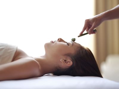 A woman receives a facial treatment with a tool at Peppers Seminyak
