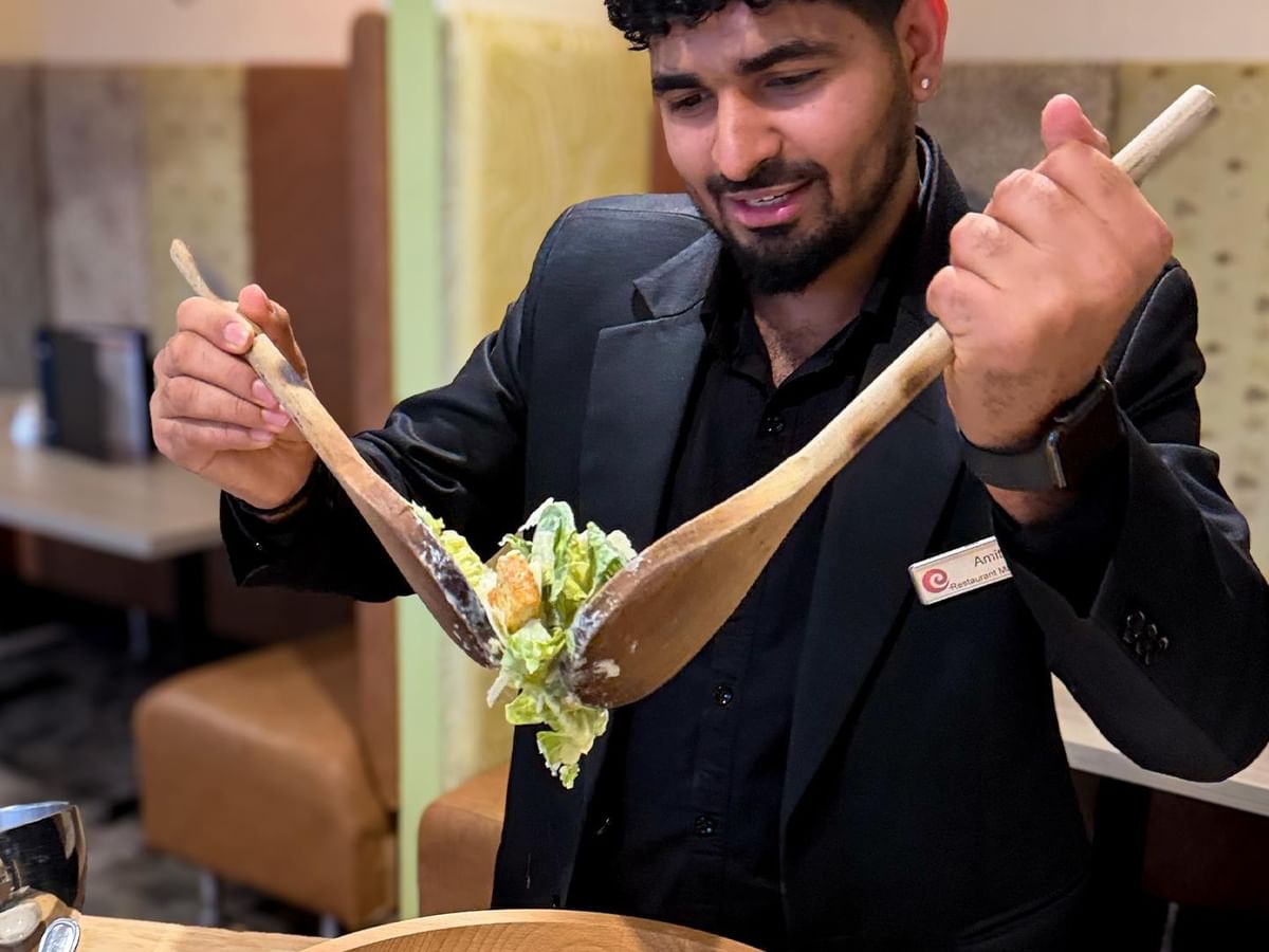 Chef preparing salad with wooden spoons at Minnoz Restaurant + Lounge, Coast Bastion Hotel in Nanaimo.