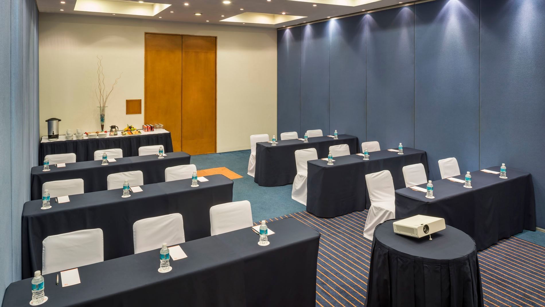 Classroom set-up with a refreshment corner and carpeted floors in the Berlin Venue at Real Inn San Luis Potosi