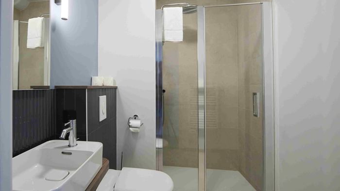 Salle de bain moderne avec douche en verre et lavabo à l'Hôtel La Marébaudière.