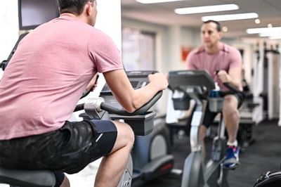 A man on an exercise bike in the gym, Nesuto Canberra Apartment