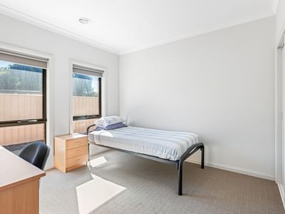 A clean single room with a bed, desk, and window at La Trobe University Regional Housing – Mildura.