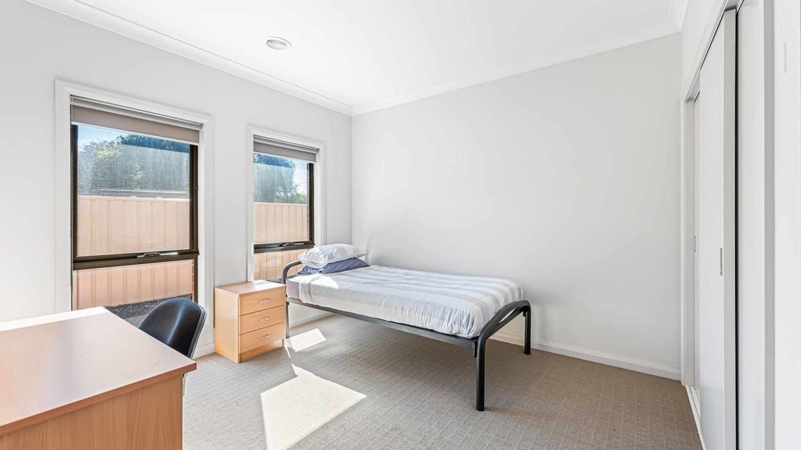 A clean single room with a bed, desk, and window at La Trobe University Regional Housing – Mildura.