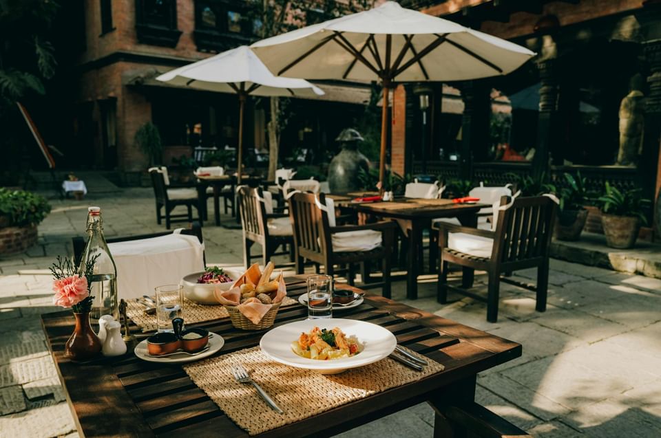 Outdoor dining table with a gourmet dish, bread basket, in the Dwarika's Courtyard at Dwarika's Hotel Kathmandu