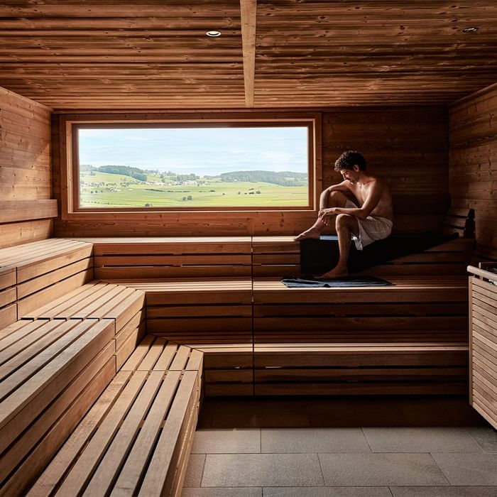 Man relaxing in the wooden sauna at Falkensteiner Genuss & Wohlfühlhotel Mühlviertel