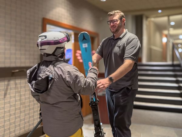Skier handing skies to a hotel staff member